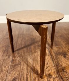 a round wooden table sitting on top of a hard wood flooring covered in light brown stain