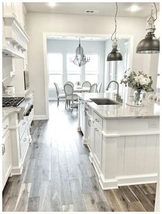 a large kitchen with white cabinets and wood flooring is seen in this image from the front door