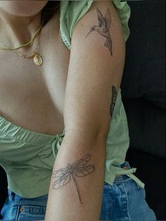 a woman's arm with tattoos on it and a hummingbird tattooed on the arm