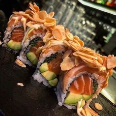 three sushi rolls with avocado, cucumber and almonds on top