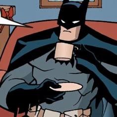 a batman sitting in a chair with his hands on his chest