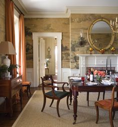 a dining room with a fireplace, table and chairs in front of a painting on the wall