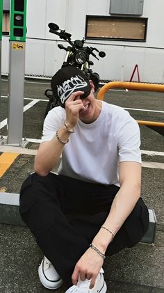 a young man sitting on the ground with his head in his hands and wearing a helmet