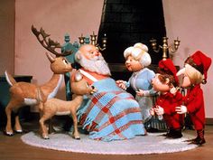 a group of dolls sitting on top of a table next to a christmas tree and reindeer