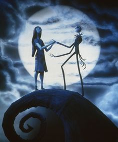 two people standing on top of a hill in front of a full moon