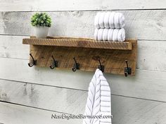 a towel rack with hooks on the side of a wall next to a potted plant