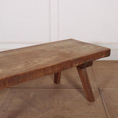 a wooden bench sitting on top of a hard wood floor next to a white wall