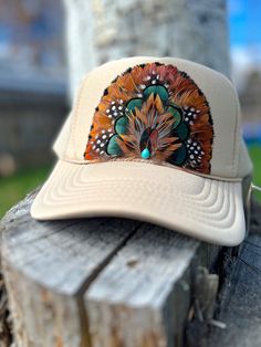 the hat is sitting on top of a piece of tree stump with feathers painted on it