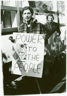 a man holding a sign that says power to the people with two other men behind him