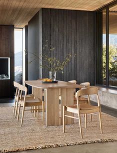 a dining room table and chairs in front of a window with mountain view behind it