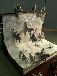 an open book with paper cut out of it and toy figurines on top