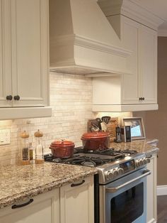 a kitchen with white cabinets and granite counter tops, an oven and stove top in the center