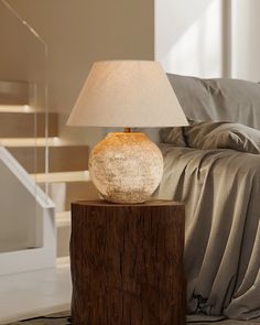 a table lamp sitting on top of a wooden block next to a bed in a living room