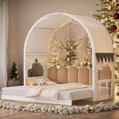 a white bed sitting next to a christmas tree in a room with lights on it