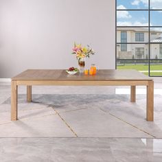 a wooden table with flowers and fruit on it in front of a large glass window