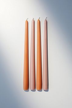 three candles sitting next to each other on top of a white surface with one orange candle in the middle