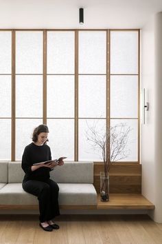 a woman sitting on a couch reading a book