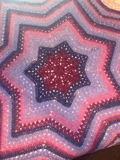 a crocheted blanket is laying on the floor