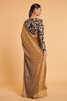 Gold net saree with sequins hand embroidery. Comes with a black tussar blouse. - Aza Fashions Traditional Sequined Saree For Evening, Traditional Evening Saree With Sequins, Traditional Sequined Evening Saree, Evening Sequin Saree Fabric With Mirror Work, Evening Sequin Fabric With Mirror Work For Saree, Traditional Drape Sequin Fabric With Mirror Work For Evening, Evening Saree With Resham Embroidery And Sequins, Evening Blouse Piece With Resham Embroidery For Festivals, Evening Blouse Piece With Zari Work For Diwali