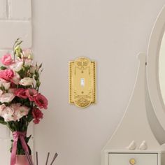 a vase filled with flowers next to a white dresser and mirror on top of a wooden table