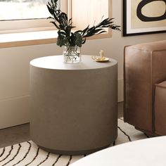 a vase with flowers on top of a table next to a chair in a living room