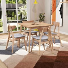 a dining table with four chairs and a rug on the floor in front of it