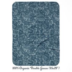 the organic double gauze is shown with dinosaurs and stars in blue, on a white background