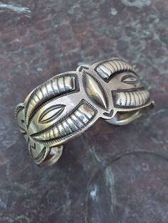 "Here is a stunning example of UITA work. This cuff is marked UITA 22 and was made by a Native American employed by Dean Kirk. This cuff has 8 areas of repoussé arranged in an eye catching way. This cuff is great to wear in a stack, but stands alone on its own. Ca 1940s Interior Circumference: 5 1/2\" not including gap of 1 1/8\" This cuff can be adjusted some. Height: 1 1/16\" Weight: 48g" Bohemian Cuff Bracelet With Polished Finish, Traditional Adjustable Cuff Bracelet With Polished Finish, Adjustable Traditional Cuff Bracelet With Polished Finish, Vintage Hand-tooled Cuff Jewelry, Silver Artisan Hand-tooled Cuff Bracelet, Silver Hand-tooled Artisan Cuff Bracelet, Artisan Silver Cuff Bracelet Hand Tooled, Artisan Hand-tooled Silver Cuff Bracelet, Traditional Adjustable Cuff Bracelet With Concho