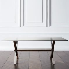 a glass table sitting on top of a hard wood floor next to a white wall