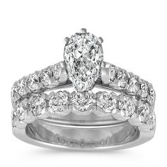 a wedding ring set with a pear shaped diamond in the center and side stones on each band