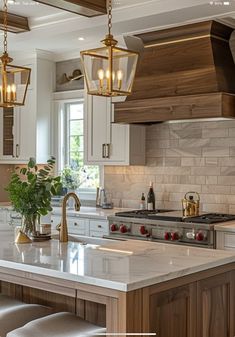 a kitchen with white cabinets and marble counter tops, two pendant lights hanging over the island