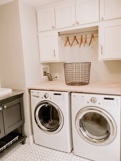 a washer and dryer in a laundry room with cabinets above the washer