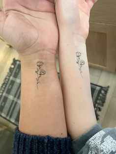 two people holding hands with tattoos on their arms and one has a flower tattoo on the wrist