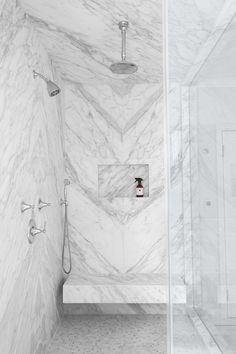 an instagram photo of a bathroom with white marble walls and floor, along with a shower head