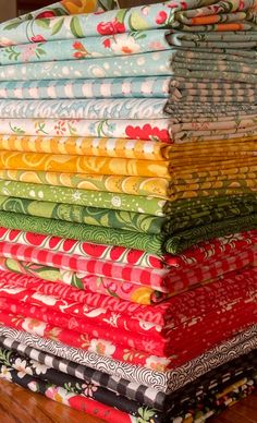 a stack of colorful fabrics on top of a wooden table