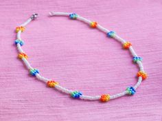 A dainty beaded necklace or bracelet with attractive and colorful rainbow daisy flowers. They are handmade with glass seed beads.   I also recommend to You: -✿-✿-✿-✿-✿-✿-✿-✿-  Check out all my daisies! ➤ DAISIES: https://www.etsy.com/shop/UnderRainbowDesign?search_query=daisy  You can find more of my rainbow jewelry here! ➤ RAINBOW: https://www.etsy.com/shop/UnderRainbowDesign?search_query=rainbow  My other floral jewelry could also be interesting! ➤ FLORAL JEWELRY: https://www.etsy.com/shop/Und White Flower Necklace With Tiny Round Beads, White Flower Necklace With Tiny Beads, Dainty White Beaded Flower Necklace, Rainbow Daisy, Black Beaded Necklace, Rainbow Jewelry, Floral Jewelry, Black Bead Necklace, Daisy Flowers