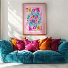 a blue couch with colorful pillows on it in front of a framed art print hanging on the wall