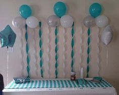 balloons and streamers are hanging from the wall above a table with a checkered tablecloth