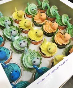 cupcakes decorated with green, yellow and blue frosting in an open box