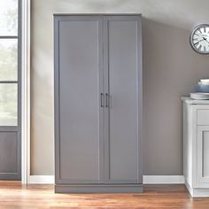 a room with a clock on the wall and a gray cabinet in front of it