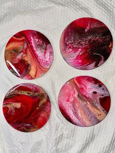 four red and black marbled buttons sitting on top of a white cloth