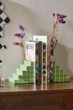 two books are stacked on top of each other in front of a vase with flowers