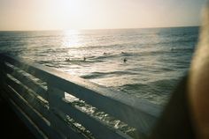 people swimming in the ocean on a sunny day with sun shining over the water behind them