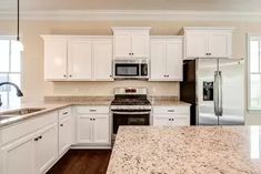 a kitchen with white cabinets and granite counter tops