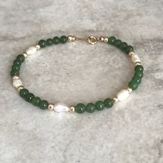 This dainty bracelet is made up with 4mm round Jade gemstone beads, Fresh Water Pearls with 3mm gold filled beads and springing clasp. The bracelet is strung on coated wire. All our jewelry is package in a gift ready pouch. This can be a perfect gift for someone special.   Suitable for daily wear that will go well with any style. All our gemstone are natural so you may see some variations in the bead size and color. If you purchases with multiple bead type, the number of beads and their arrangem Elegant May Birthstone Beaded Bracelets, Elegant Hand-strung May Birthstone Beaded Bracelets, Elegant Hand-strung May Birthstone Bracelets, Dainty Green Gemstone Beaded Bracelets, Elegant May Birthstone Bracelets, May Birthstone Hand-strung Round Bead Bracelets, Elegant Green Beaded Bracelets With Tiny Beads, Dainty Hand-strung Pearl Bracelet With Round Beads, 14k Gold-filled Beaded Bracelets With 8mm Beads As Gift