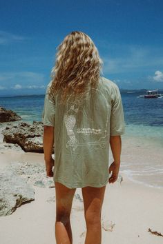 Model at the beach wearing a sun hat and showing the back of her t-shirt, a sage green t-shirt with mermaid illustration Surf Suit, Cheeky Bikinis, Large Bust, Measurement Length, The Outdoors, Oversized Fits, Sage Green, Positive Vibes, Your Skin