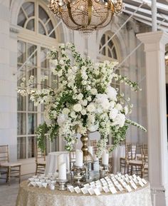 a table topped with lots of white flowers next to a chandelier filled with candles