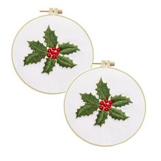 two embroidered christmas holly leaves with red berries on white hoop - shaped wall hangings