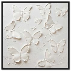 some white butterflies on a wall with black trimmings and a black framed frame