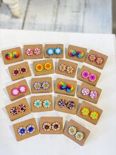 there are many different pairs of earrings on the table next to each other and one is made out of cardboard